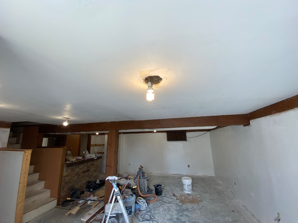 Finished basement drywall with smooth mudded ceiling, recessed lighting rough-in, and clean walls ready for paint and flooring