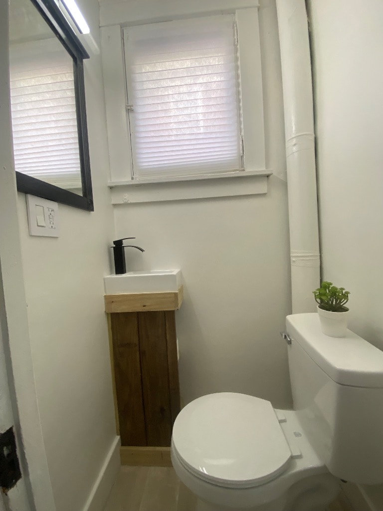 Completed half bath remodel with custom wood vanity, matte black faucet, and natural light