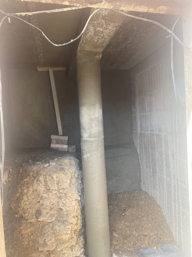 Completed concrete pier column set and cured inside a foundation cavity with vapor barrier installed on block walls