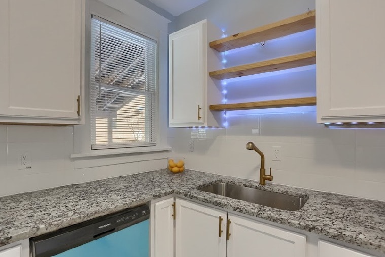 Finished kitchen remodel with white shaker cabinets, granite countertops, gold fixtures, and LED-lit open shelving