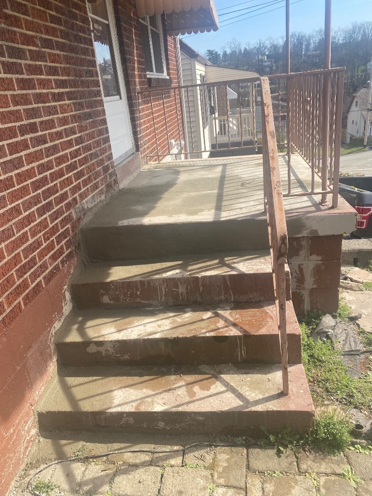 Completed resurfaced concrete porch and steps with metal railing on a Pittsburgh brick rowhouse after Set2 Go repair