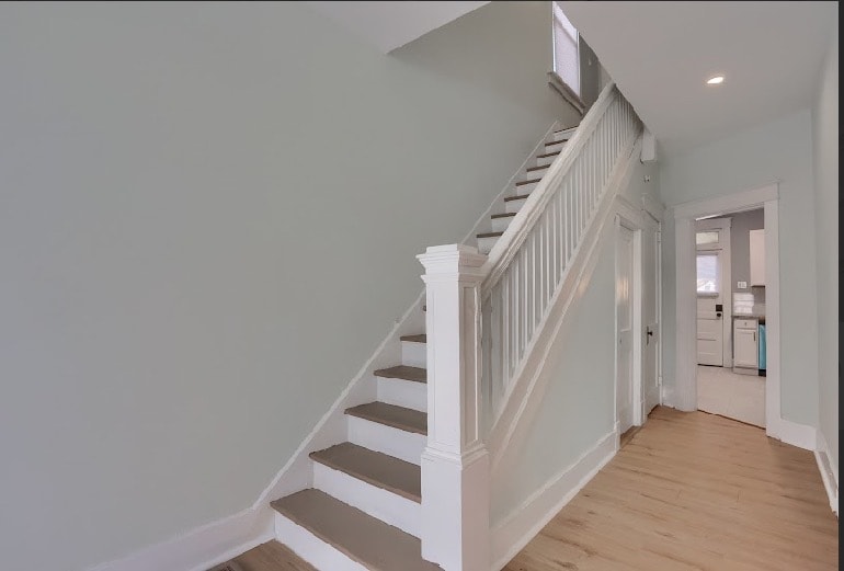 Finished living room with fresh soft gray paint, light hardwood flooring, white brick fireplace surround, and recessed lighting