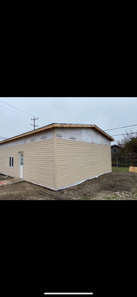 Completed new structure exterior with beige lap siding installed, door set, and roofline wrapped — near-finished build by Set2 Go
